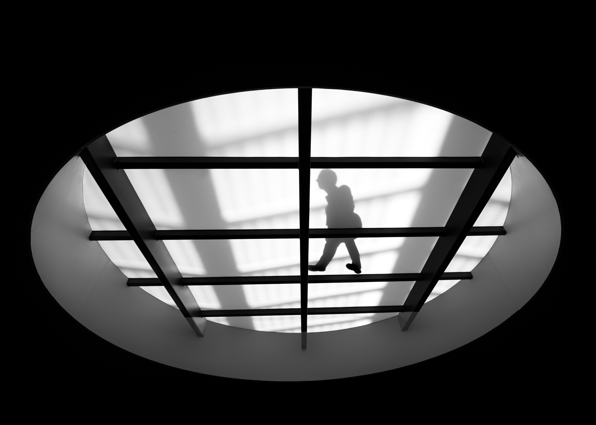 Fine art photography silhouette walking across a gridded skylight.
