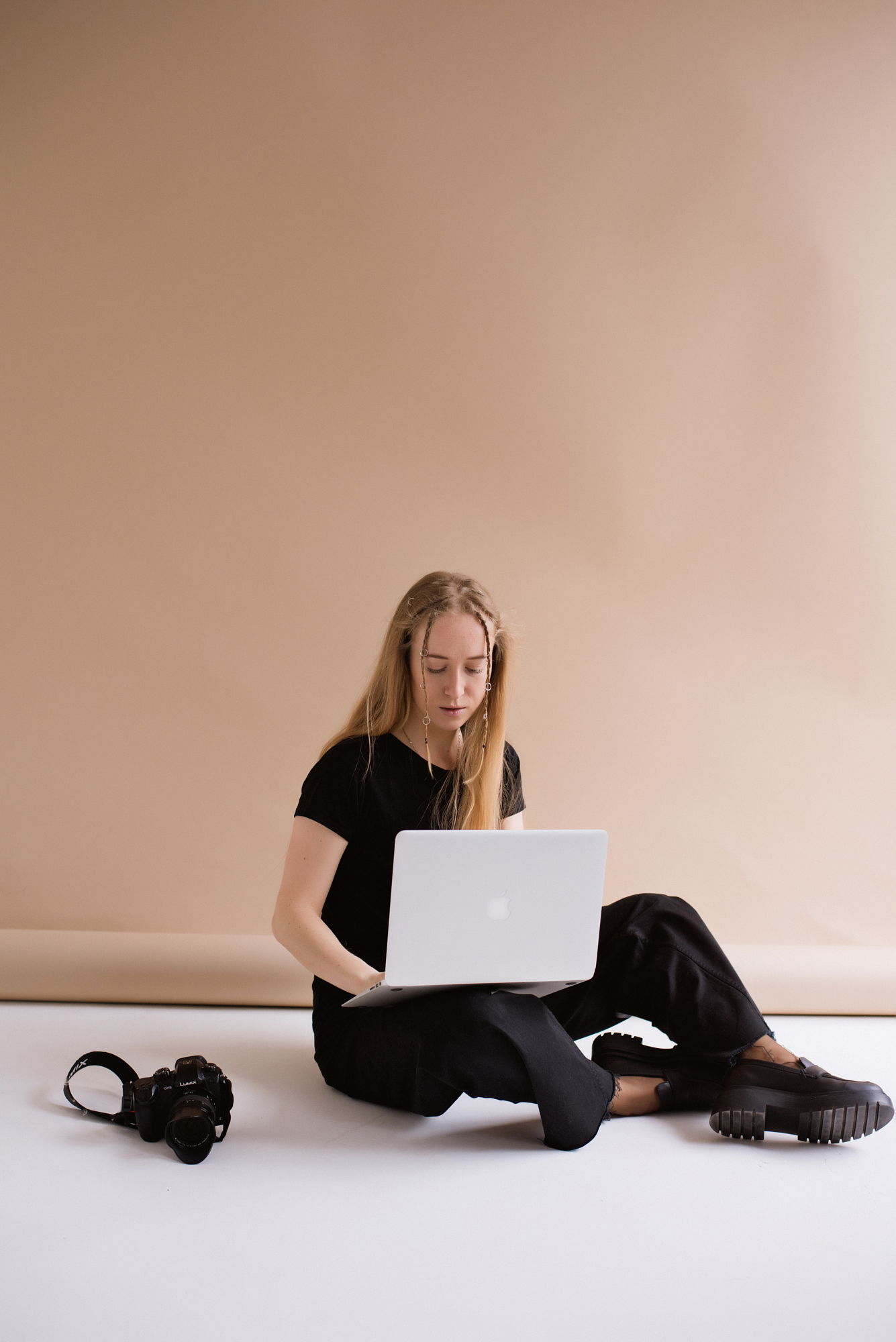 Professional photographer editing images on a laptop in a studio setting, demonstrating authentic commercial content creation.