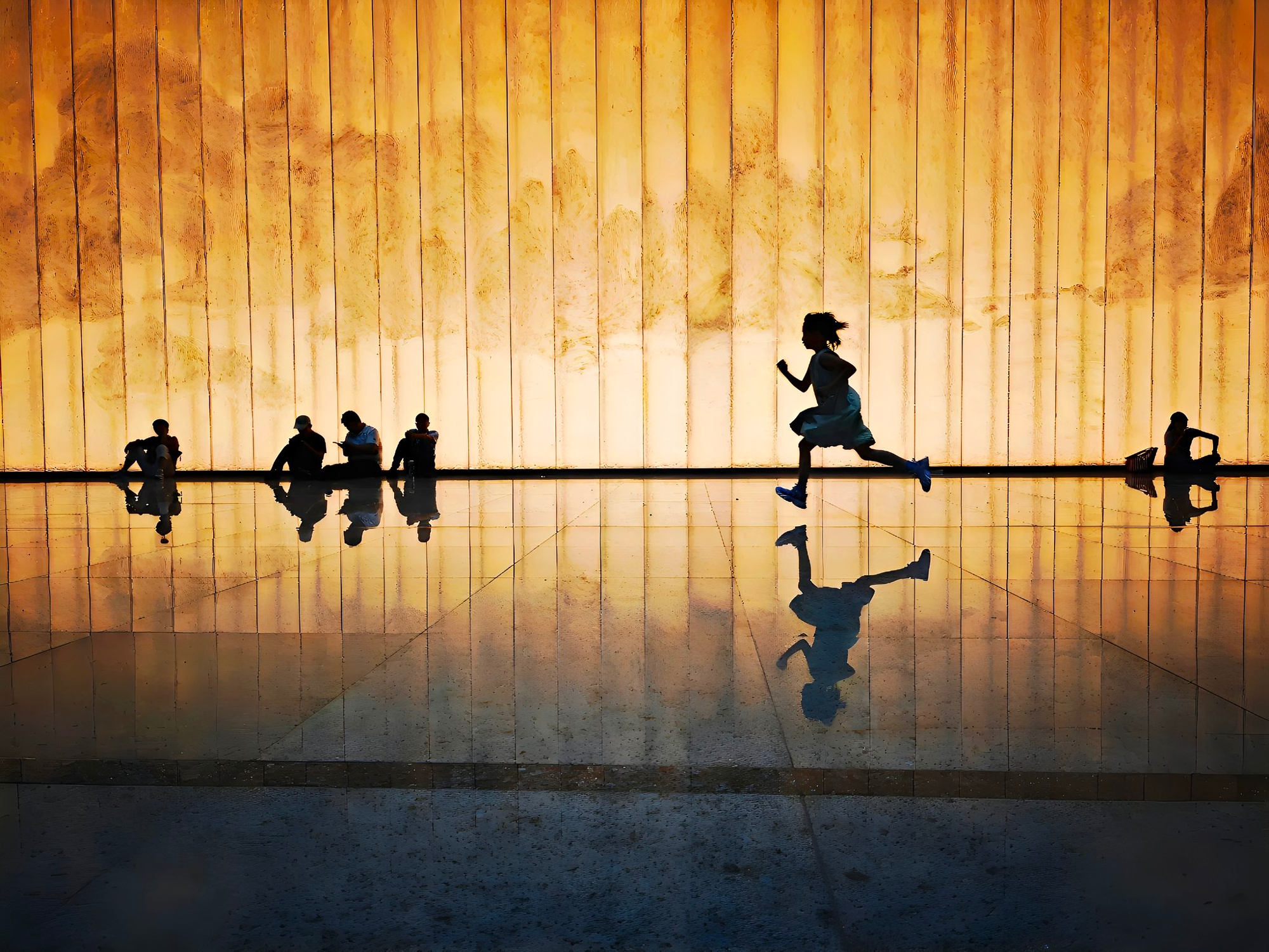 Silhouette of a running child reflected on a polished indoor floor using reflection composition techniques.