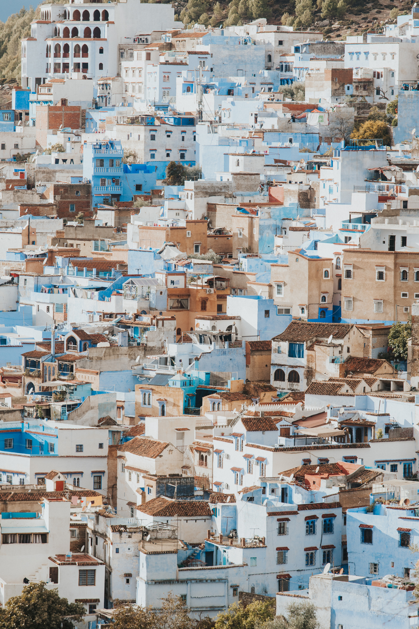 A breathtaking hillside view of the blue and white buildings crowded together in Chefchaouen, photographed by Moroccan landscape photographer Younes Ezzentri.