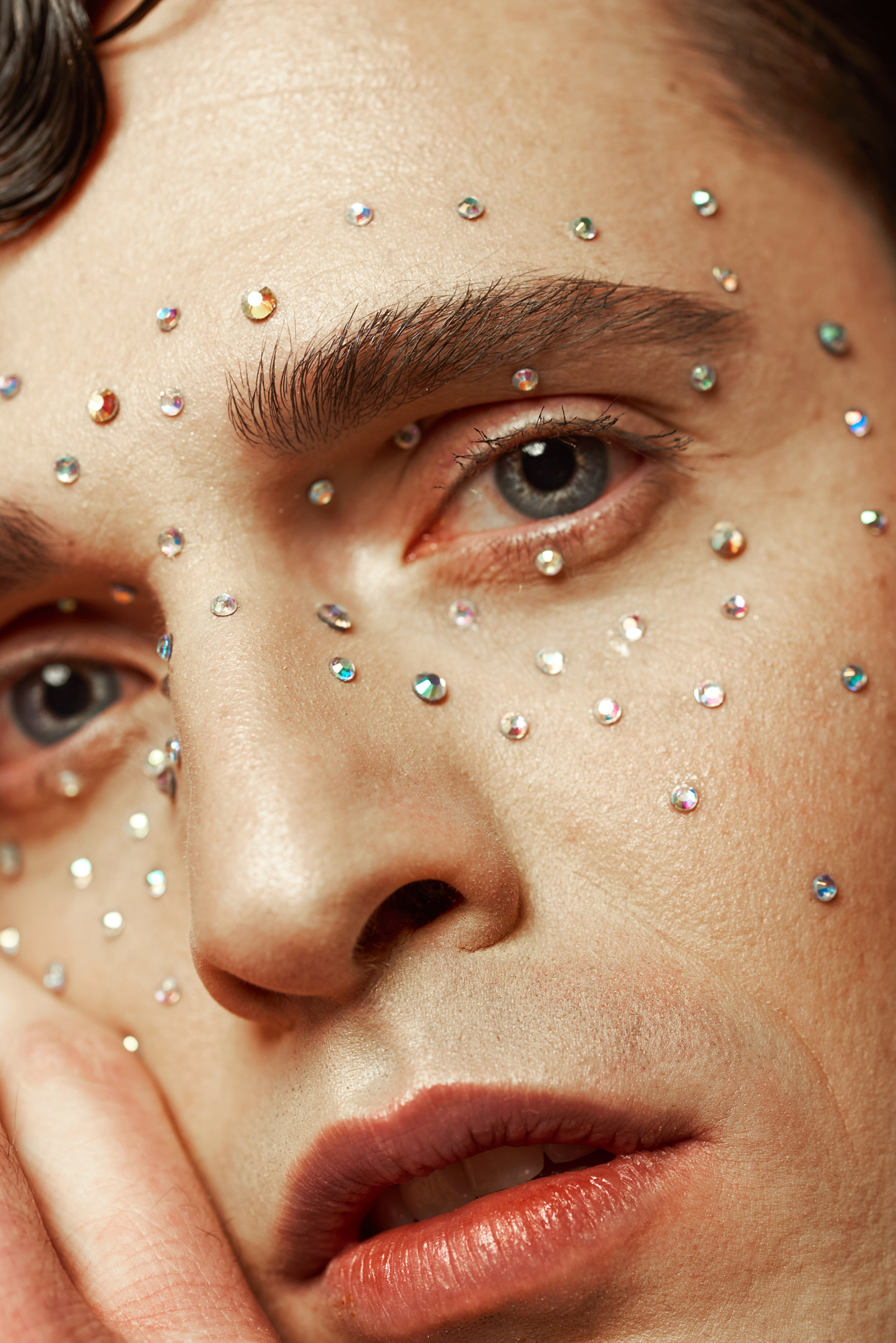 Intricate fine art portrait close-up highlighting skin detail and reflective crystal makeup embellishments.
