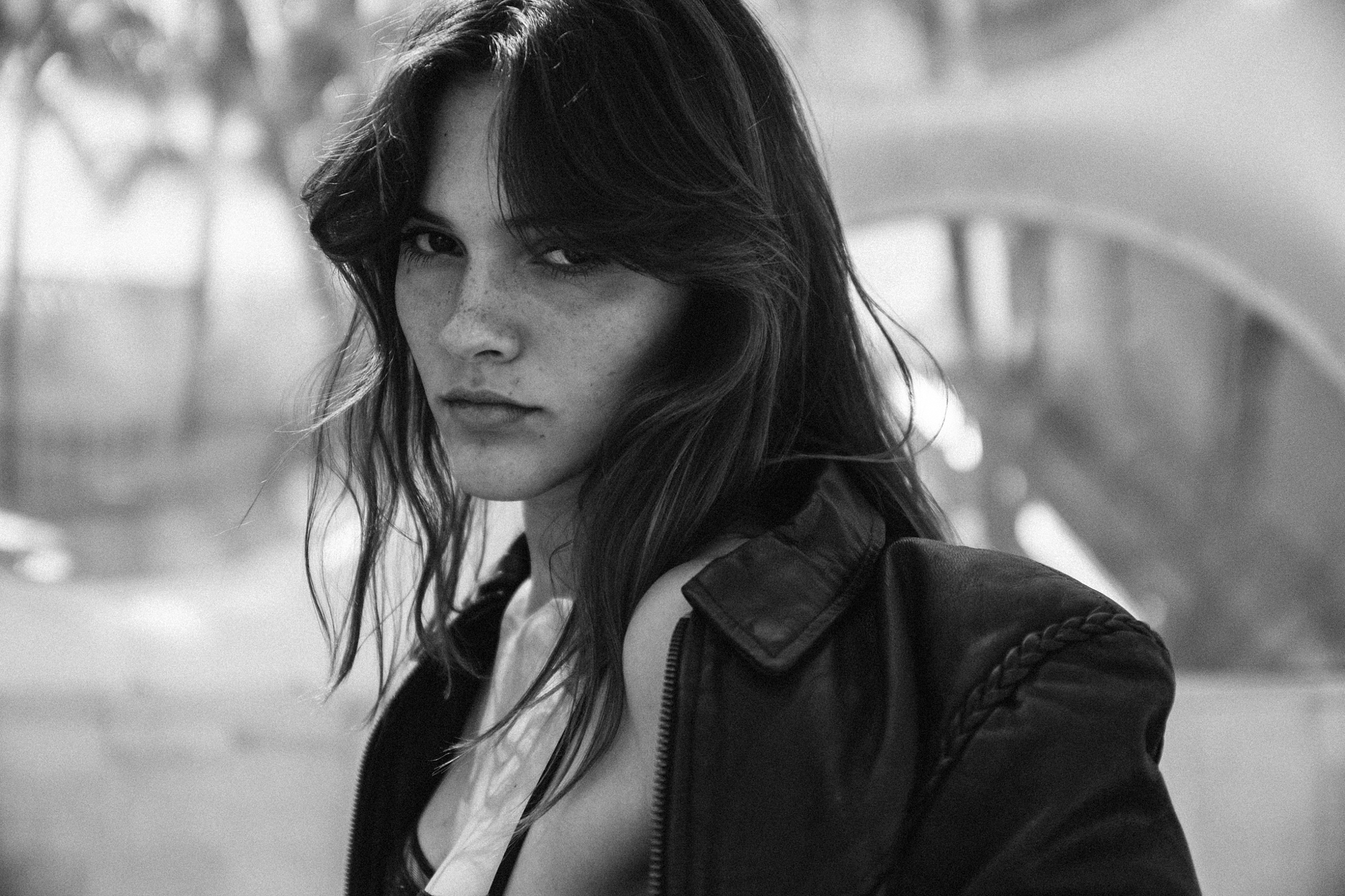 Close-up black and white fashion portrait by Holger Nitschke featuring a woman in a leather jacket with an intense gaze.