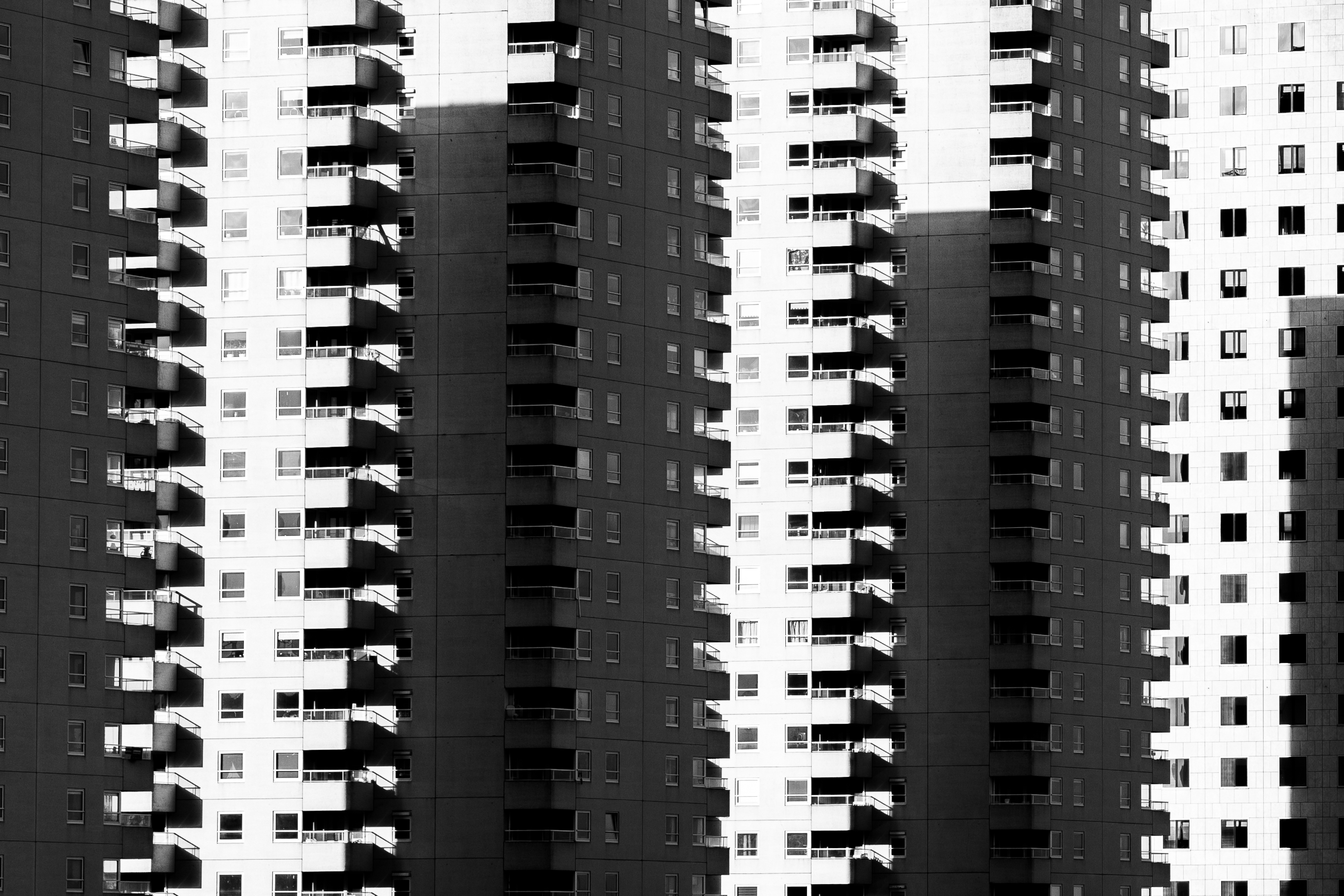 Architecture and street photography of high-rise balconies cut by hard shadow, by Martien Aerts