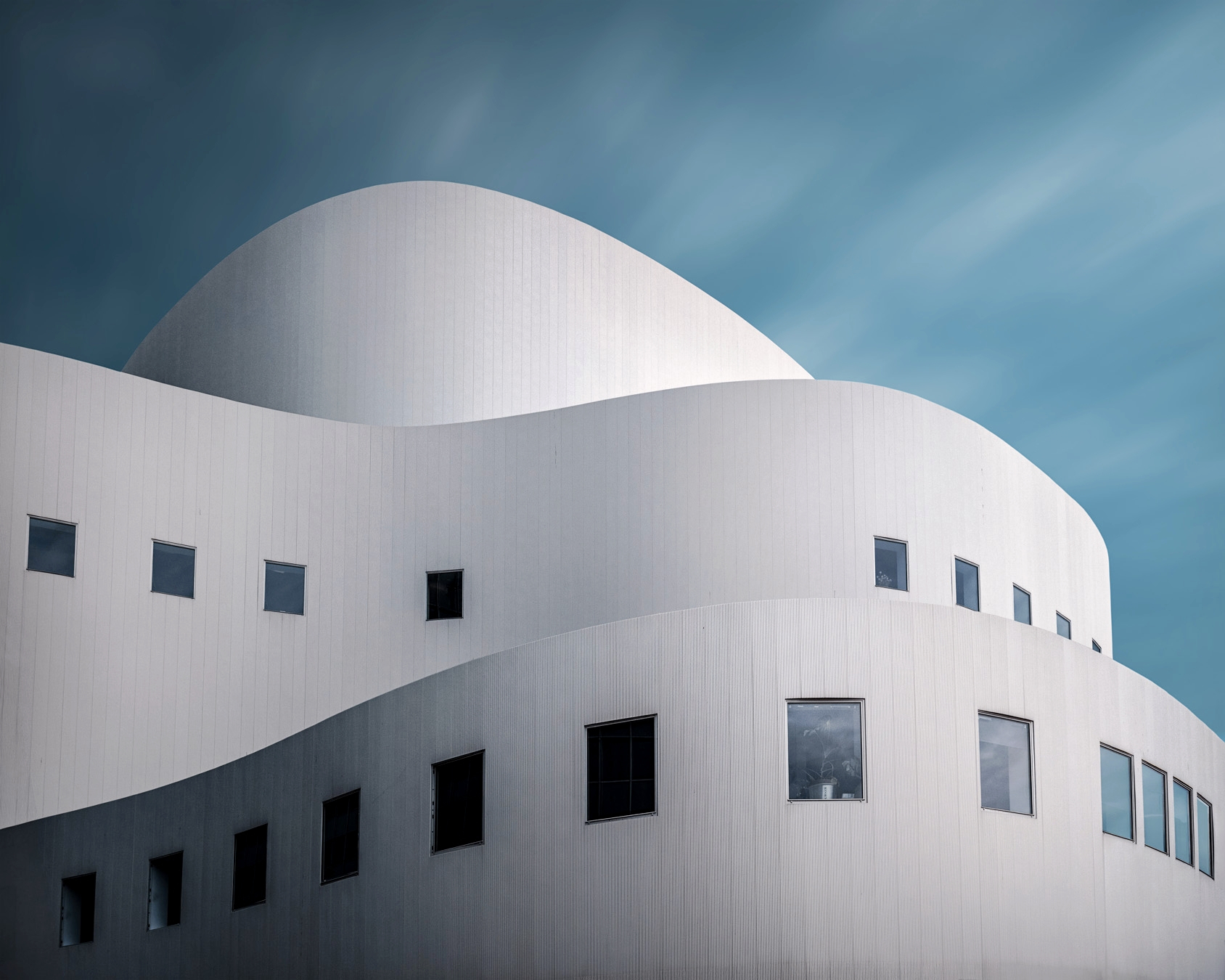 Curved white theater facade rising against a deep blue sky