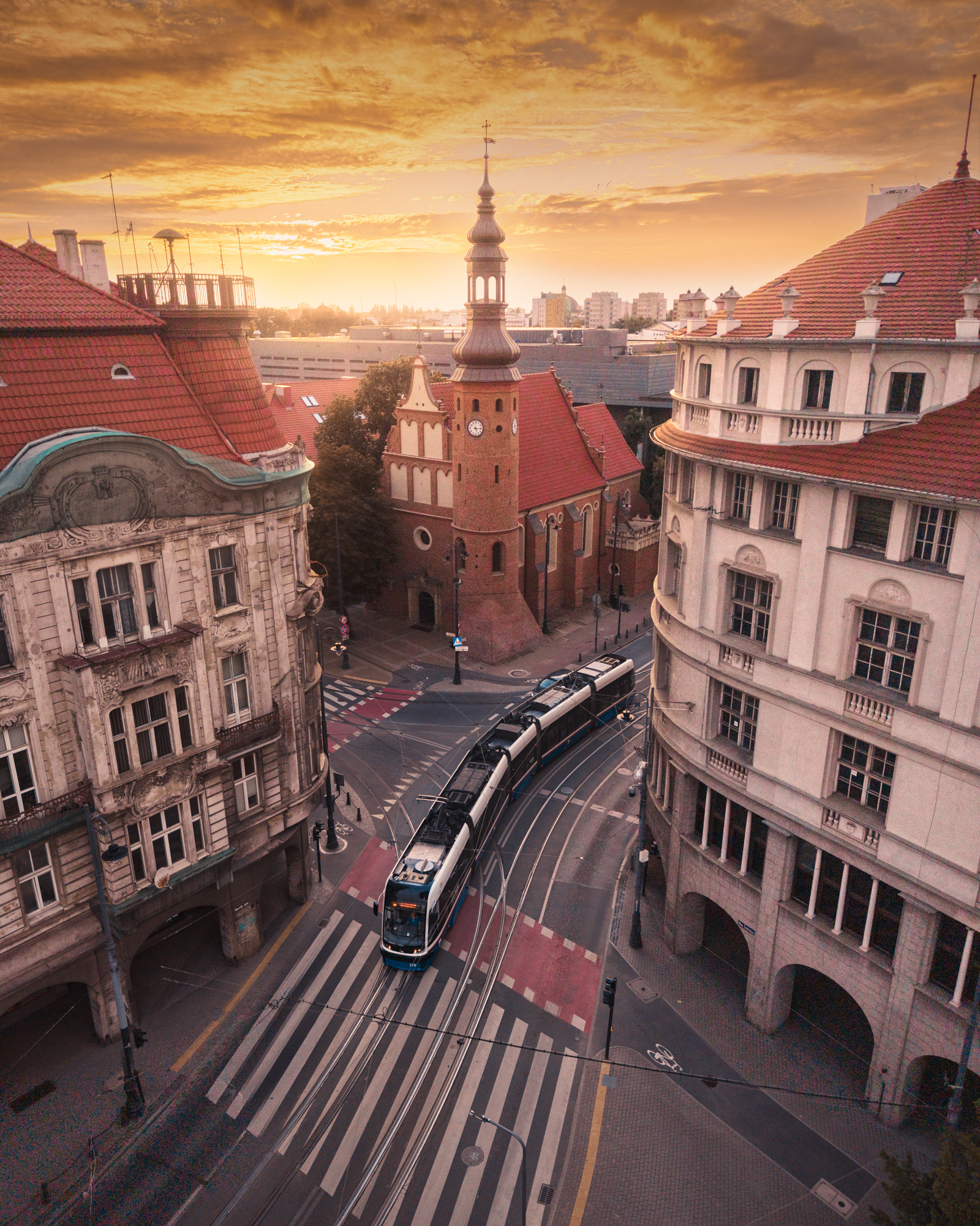 Tram photography at sunrise as a tram curves past a brick church in Bydgoszcz