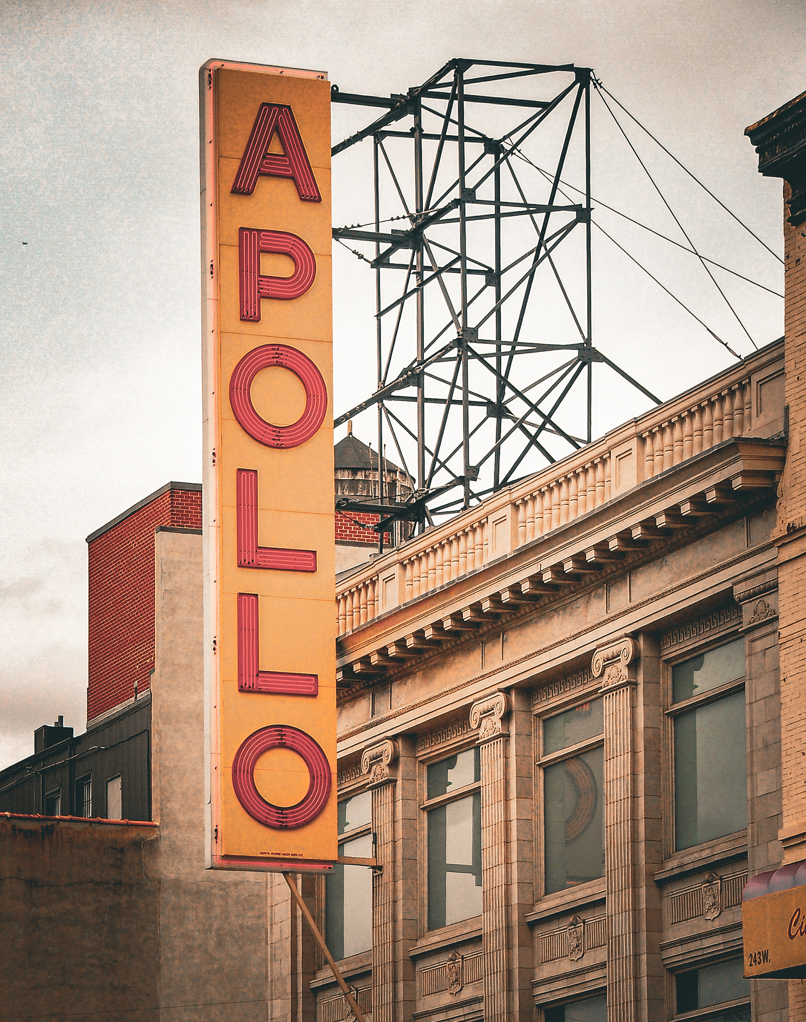 The Apollo Theater neon sign and rooftop rigging against a flat grey Harlem sky