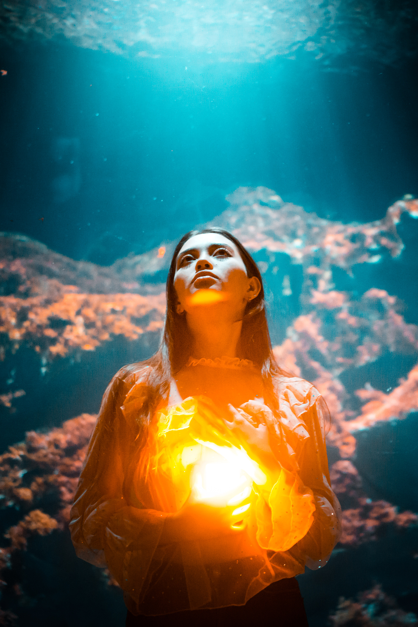 Portrait lit by a glowing orange lamp against deep blue water, classic blue and orange photography