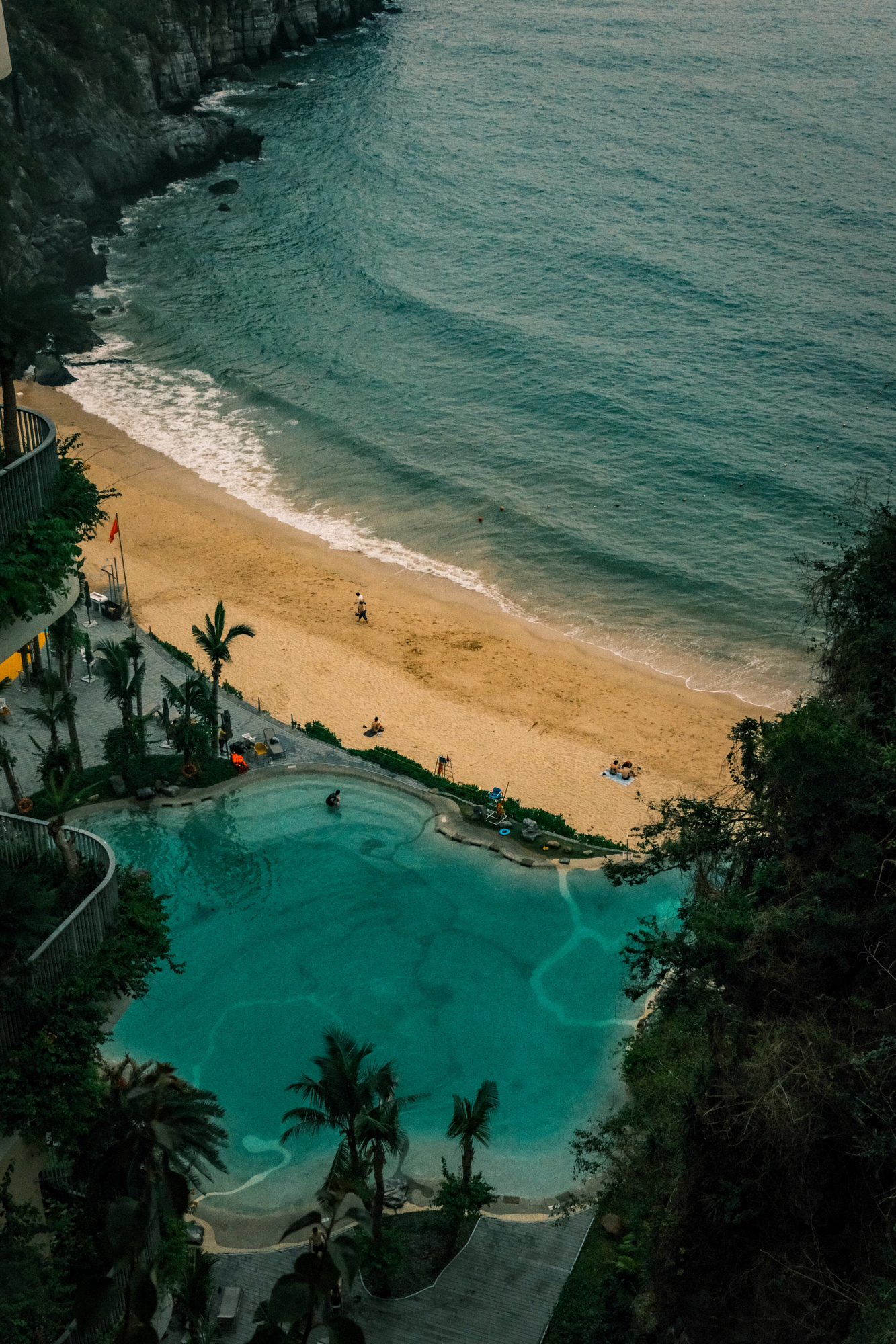 Turquoise pool and empty beach cove seen from a clifftop at dusk
