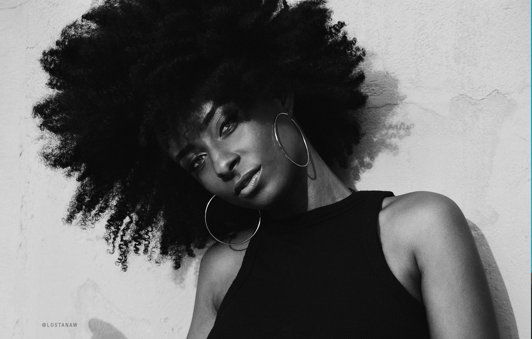 Black and white portrait of a woman with a natural afro and large hoop earrings