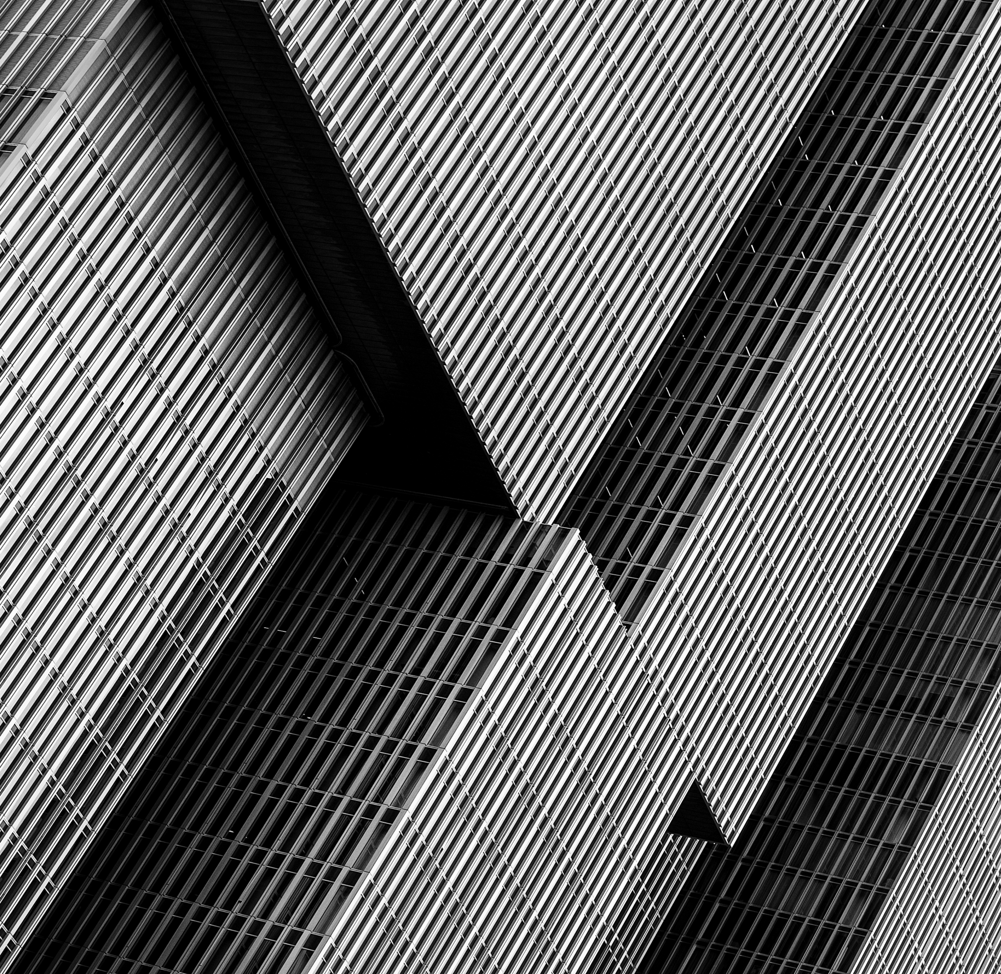 Diagonal striped facade folding into a sharp black shadow in Rotterdam