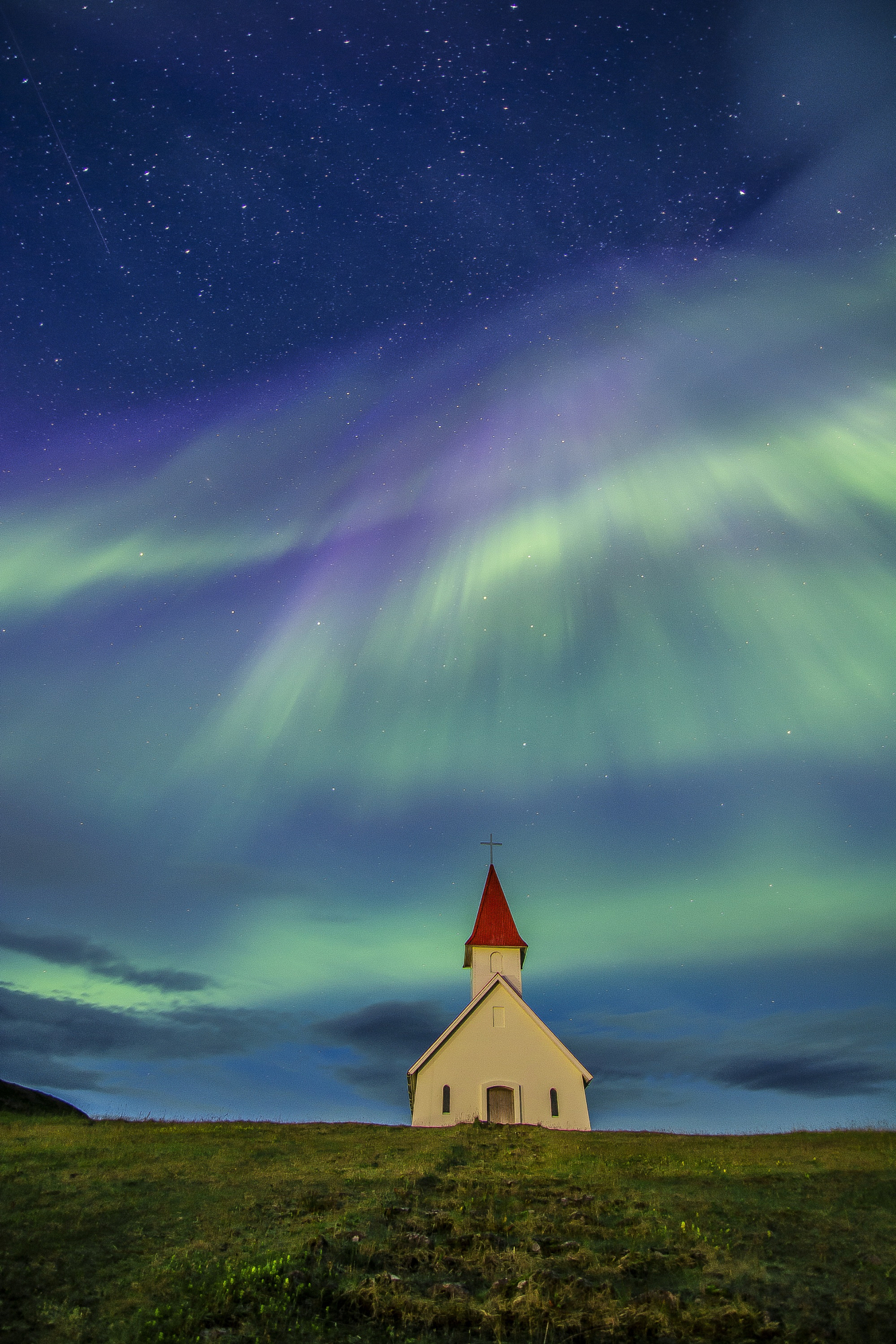 Northern Lights aurora borealis over a white church in Iceland, landscape photography by Gonzalo Bendito