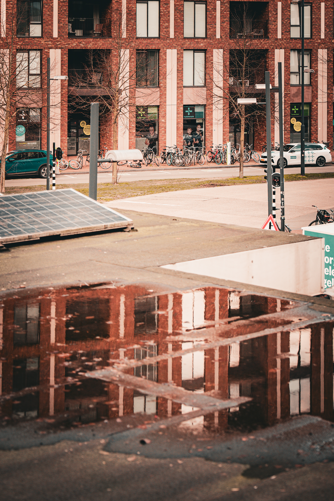 Puddle reflection of a brick facade and bikes, shot by Eindhoven photographer Martien Aerts