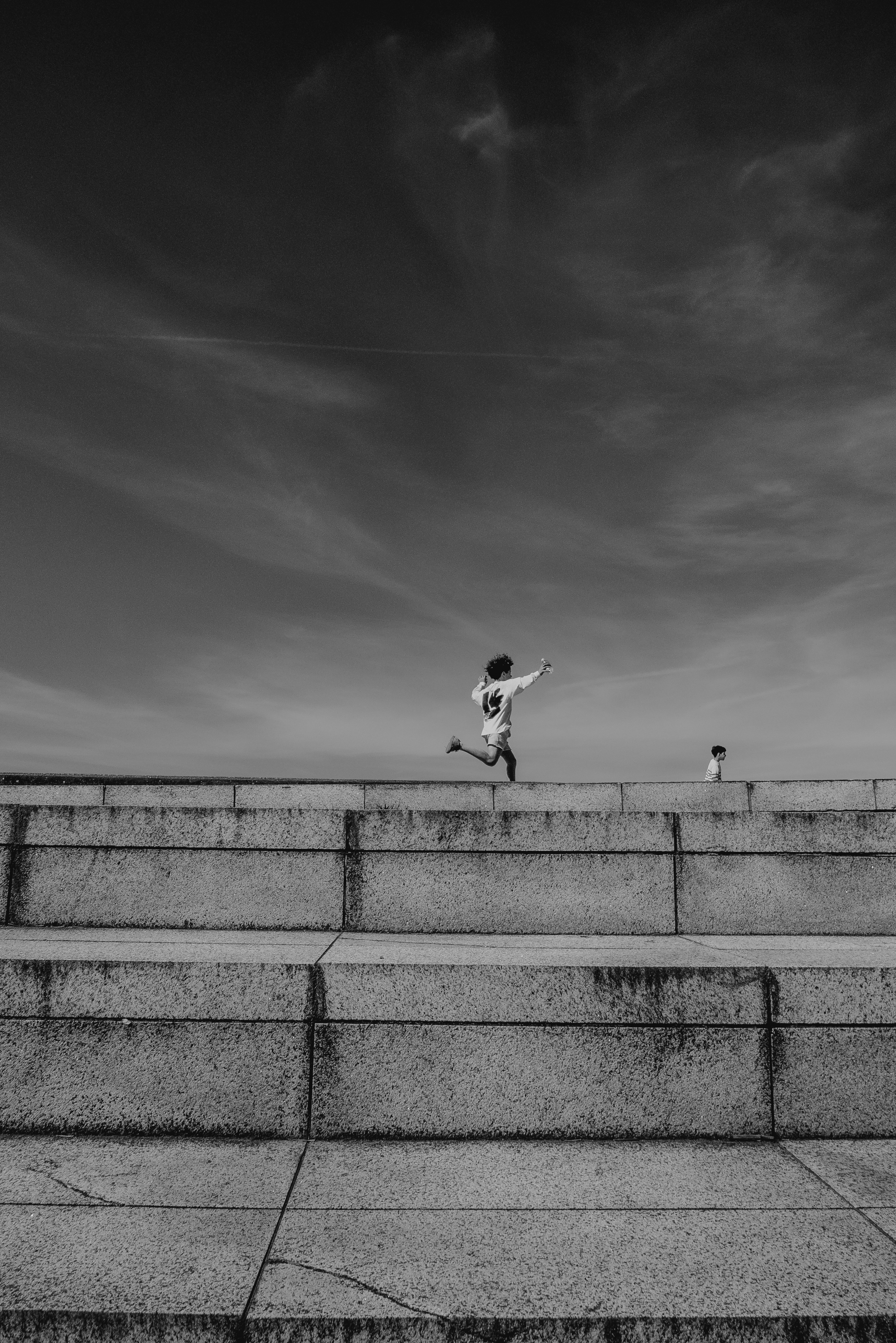 Child running along the top of a concrete wall under a wide sky, from Eline Deckers's street photography.