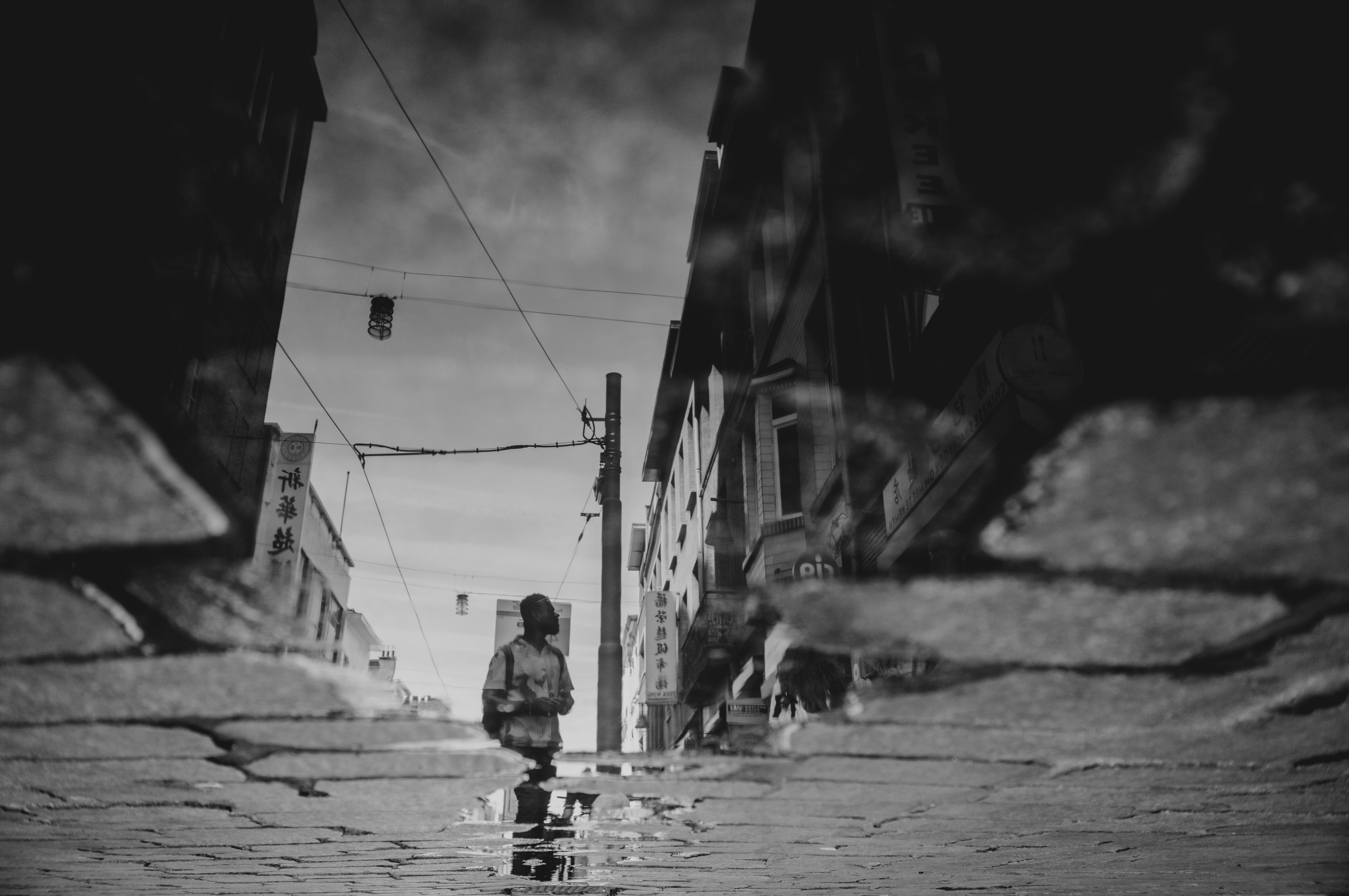 Street with Chinese signage seen upside down in a rain puddle, from Eline Deckers's street photography.