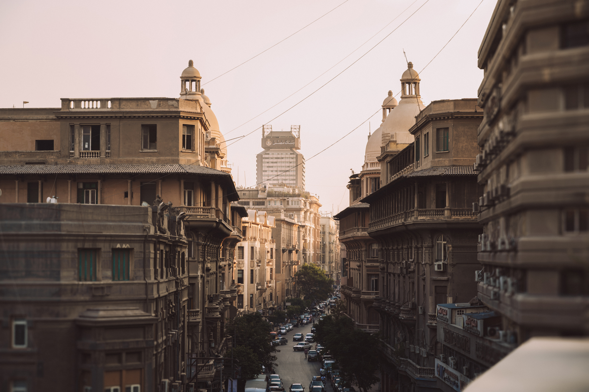 Downtown Cairo street at dusk framed by early twentieth-century domed facades, home ground for architect-turned-photographer Andrew Shenouda.