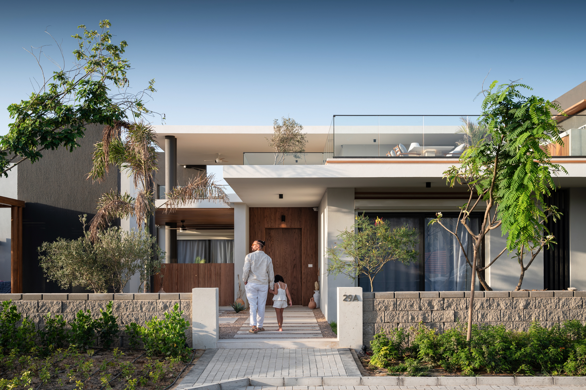 Man and child walking to the timber front door of a modern beach house, from Andrew Shenouda's residential architectural photography.