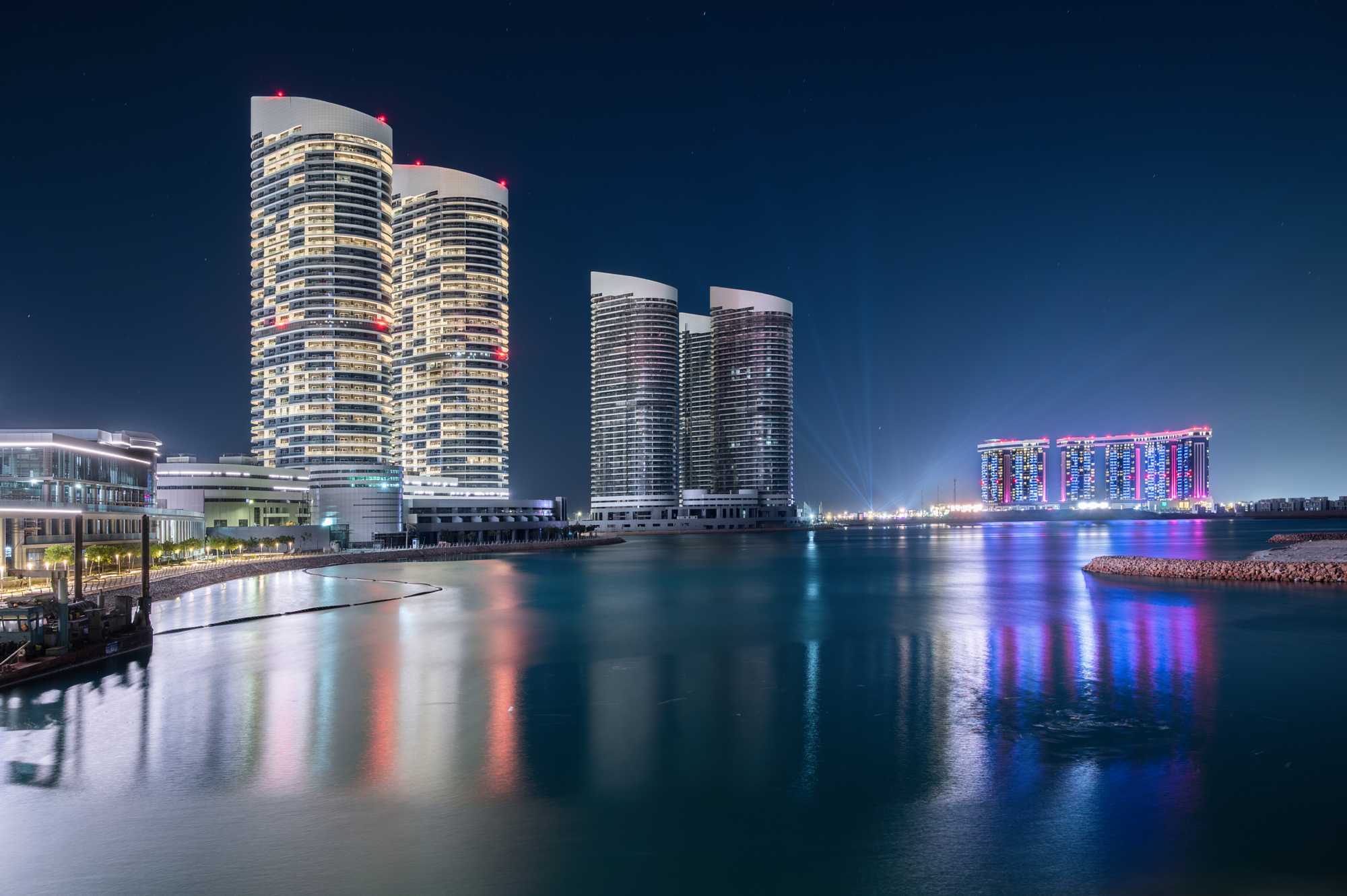 Illuminated New Alamein towers reflected in still water at night, part of Andrew Shenouda's architectural photography of Egypt's new coastal city.