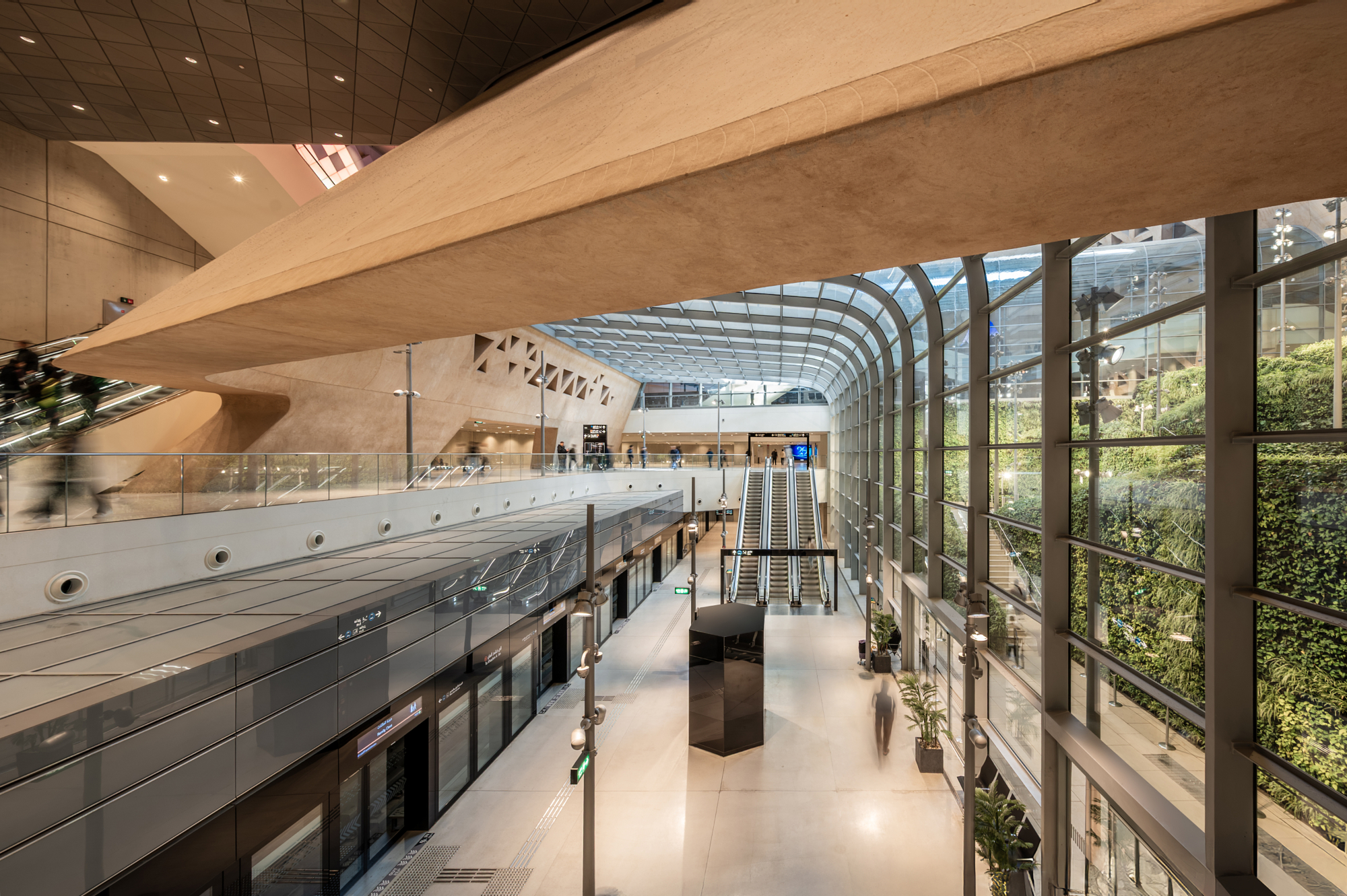 Concourse of Qasr Al Hukm Station in Riyadh with a full-height living green wall and escalators, from Andrew Shenouda's architectural photography.